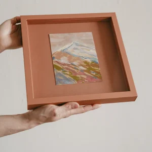 terrecotta coloured square framed pastel study of a colourful mountain