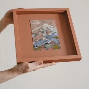 terracotta coloured square framed pastel study of a colourful mountain